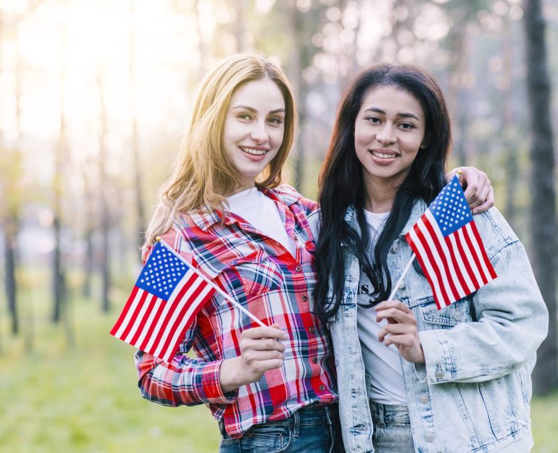 girlfriends-with-small-american-flags-standing-outdoors